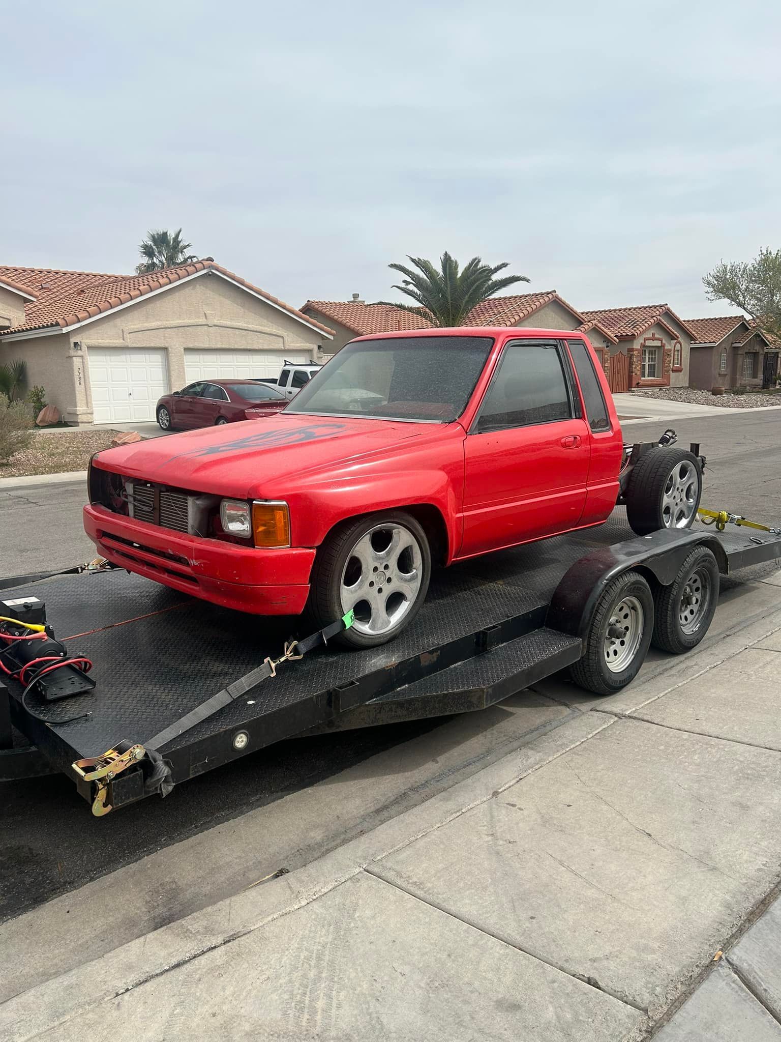 Red Pickup Truck Secured On Tow Trailer Outside Shop | Double D Automotive