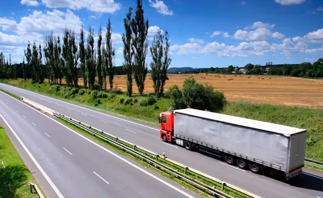Un camión semirremolque rojo y blanco circula por una autopista.