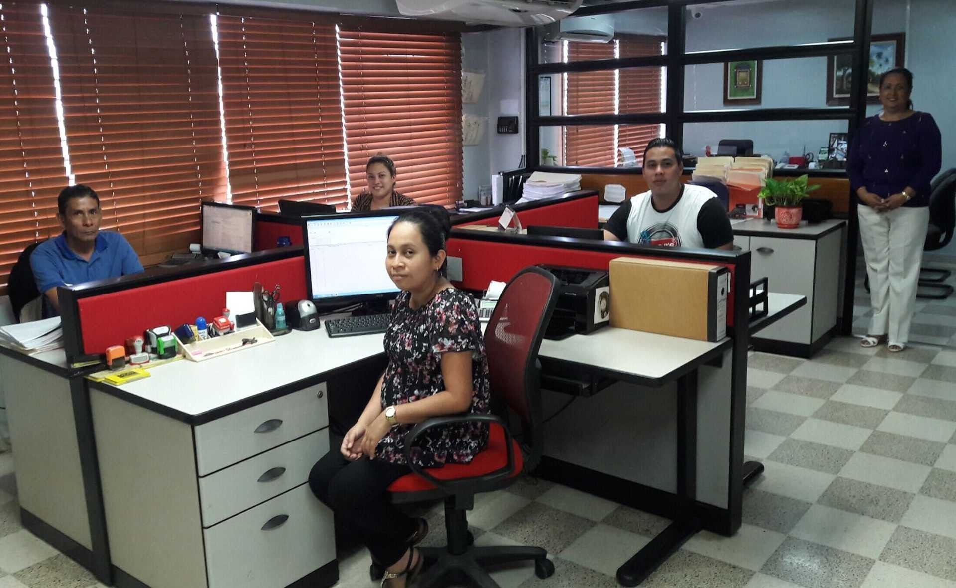 Una mujer se sienta en una silla roja en un cubículo de oficina.