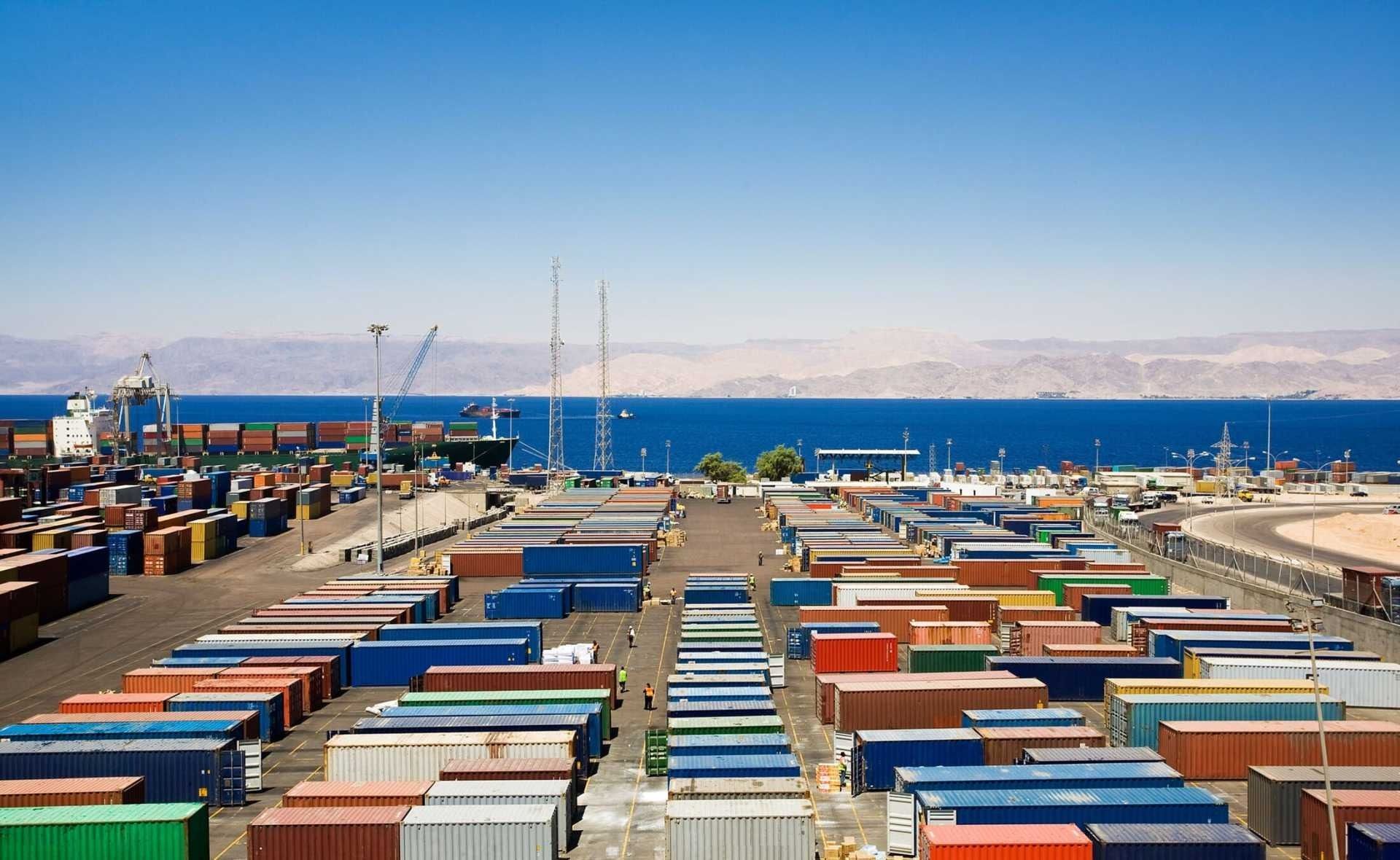 Un montón de contenedores de envío están alineados en un puerto