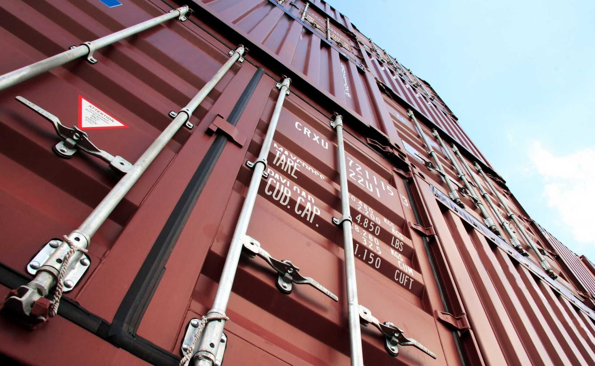 Un primer plano de un contenedor de envío rojo con un cielo azul de fondo.