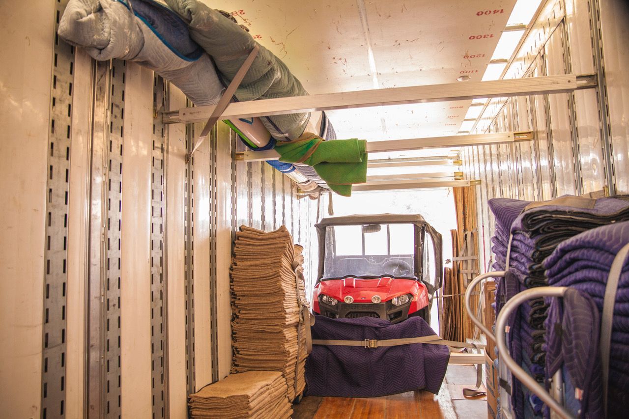 The inside of a moving truck filled with boxes and a golf cart.