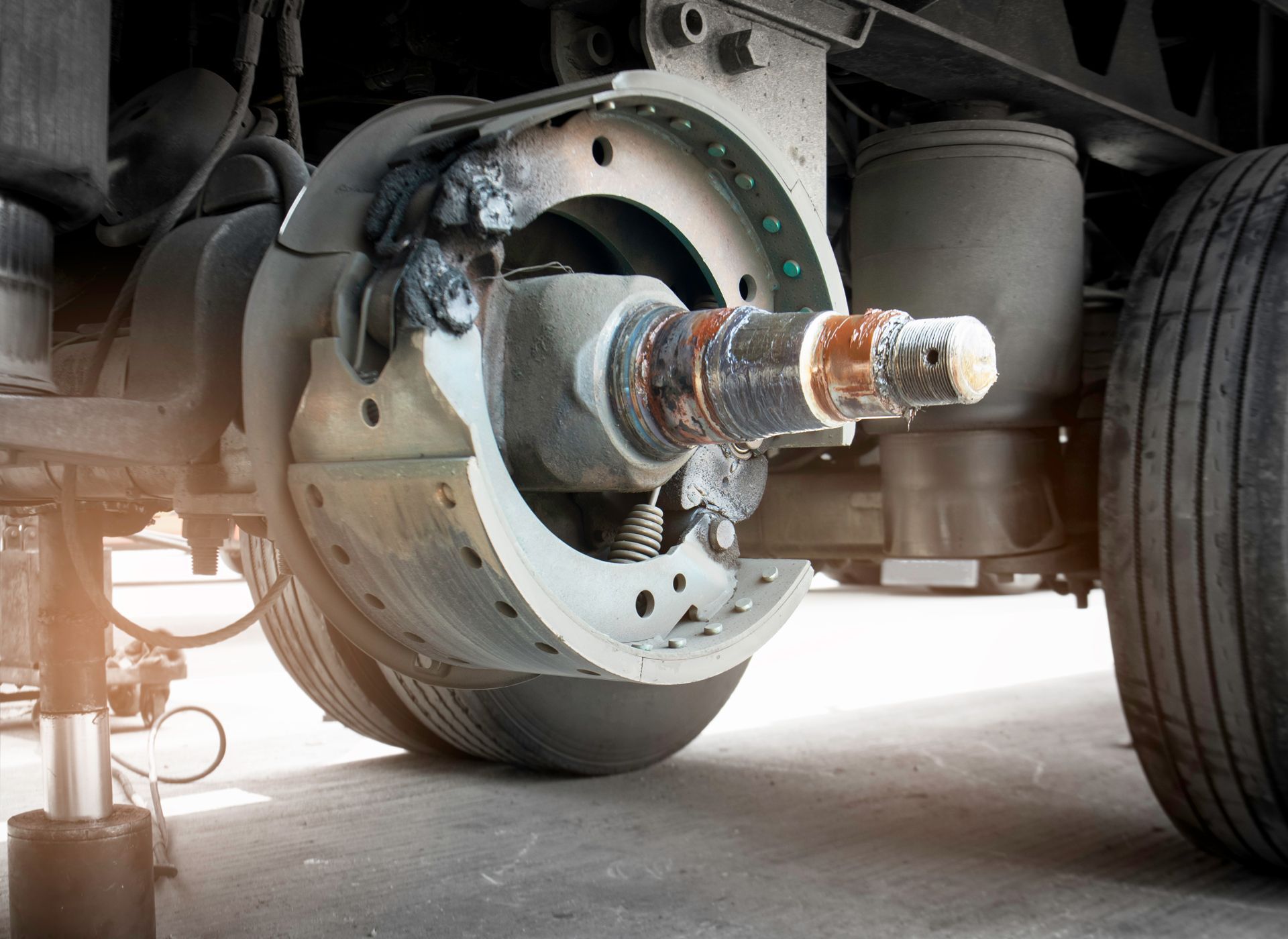 A close-up of a truck wheel hub with the brake drum removed, revealing the axle, brake shoes, and air suspension bellows.
