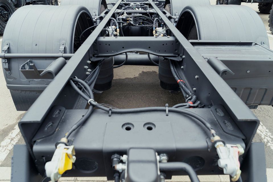 The rear chassis of a heavy-duty truck, showing the frame, rear wheels, mudguards, and air brake line connectors.
