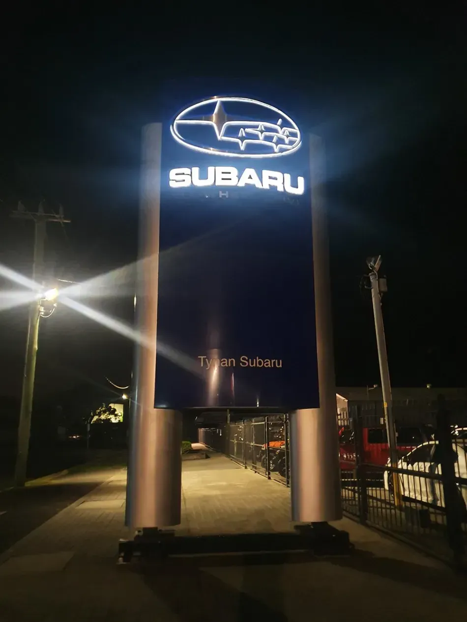 A subaru sign is lit up at night