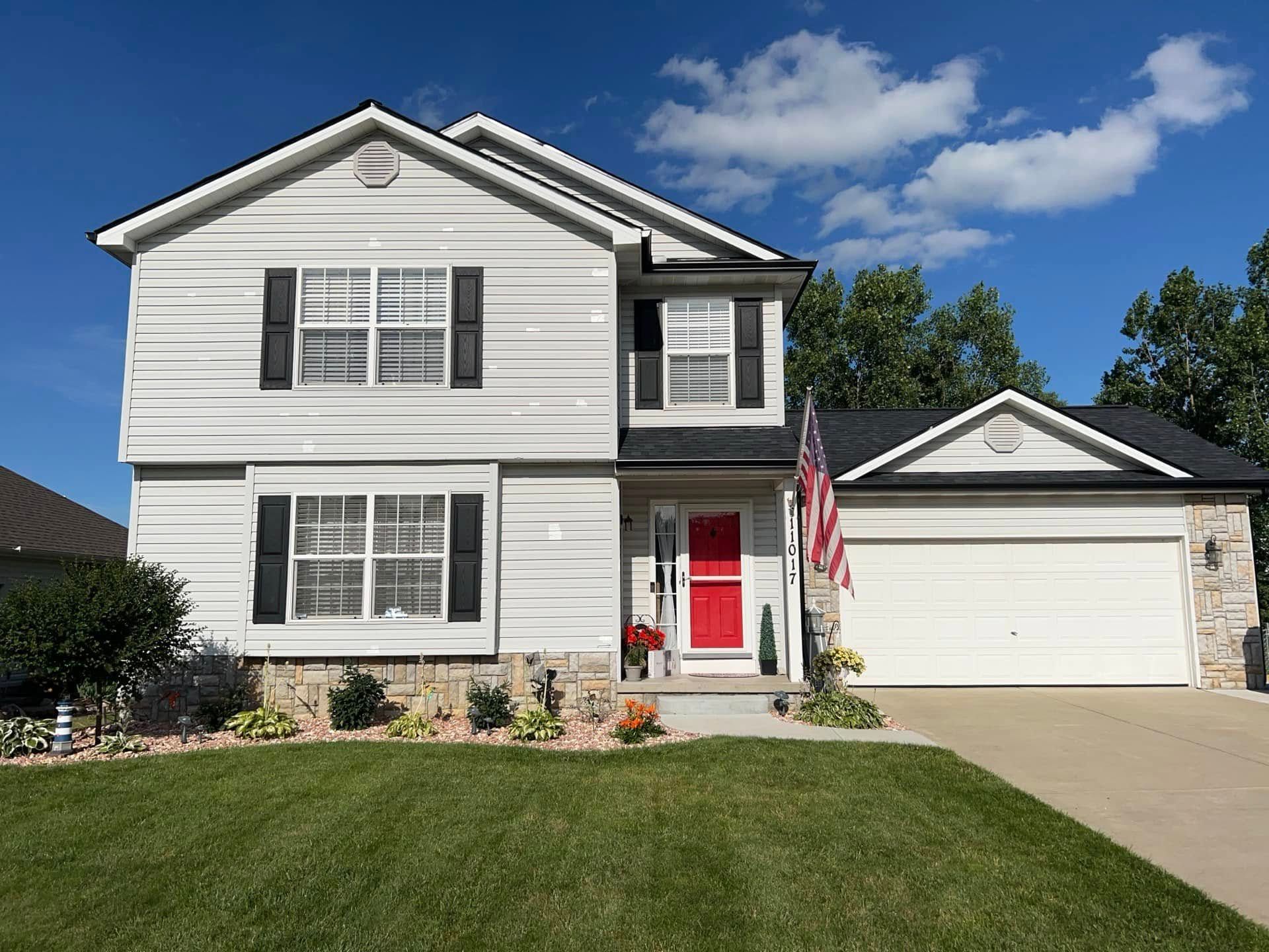 A large white house with a red door and a garage.