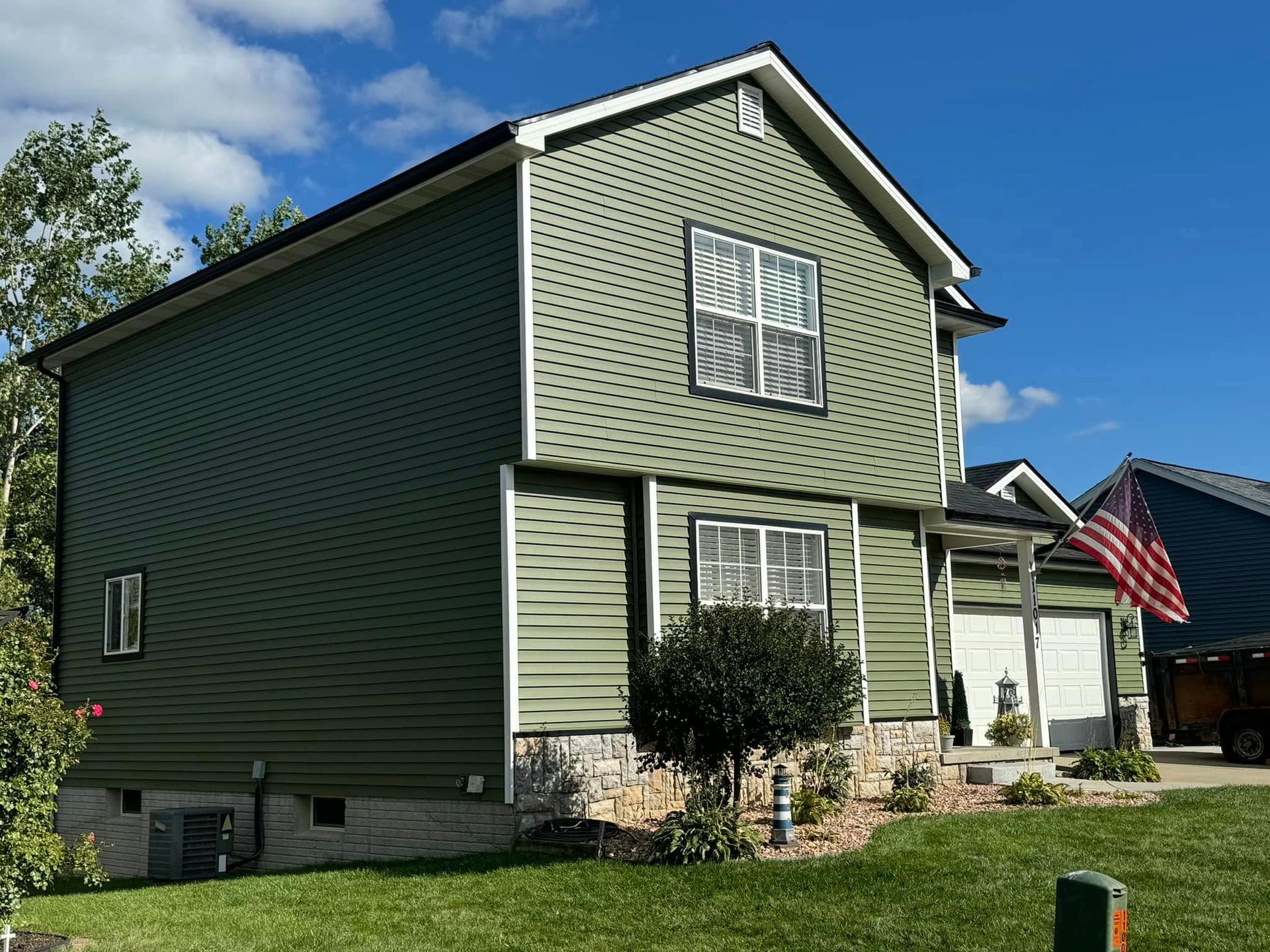 A green house with a red american flag in front of it