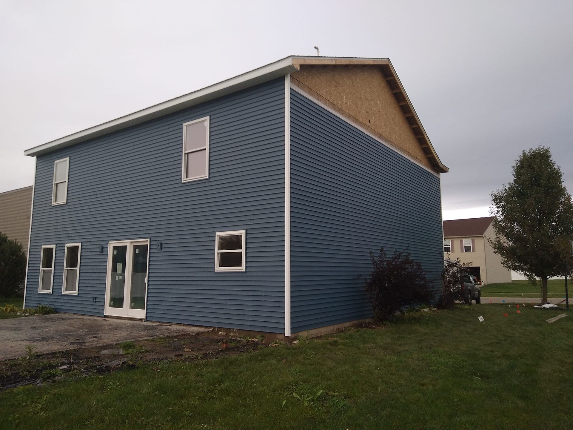 A blue house with white windows and a white gutter