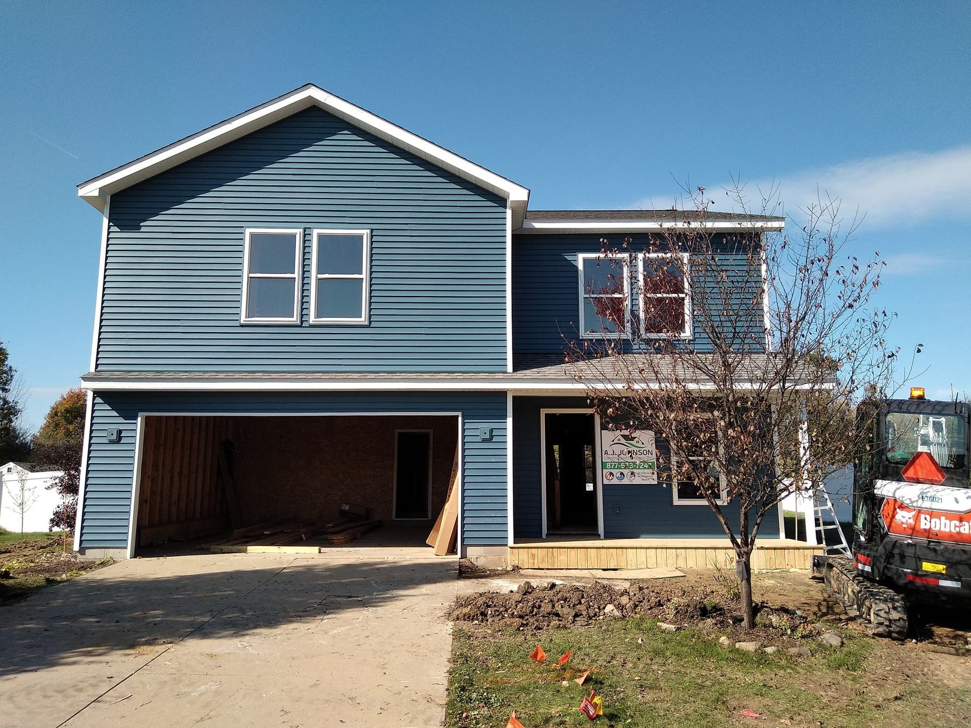 A blue house with a tractor parked in front of it