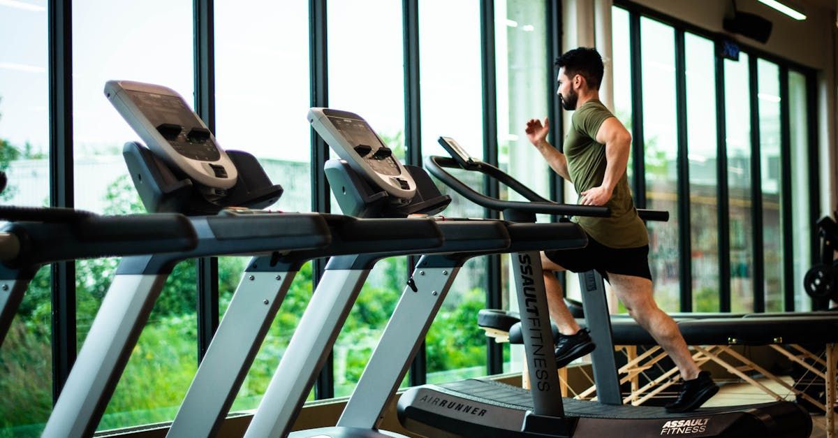 A man is running on a treadmill in a gym.