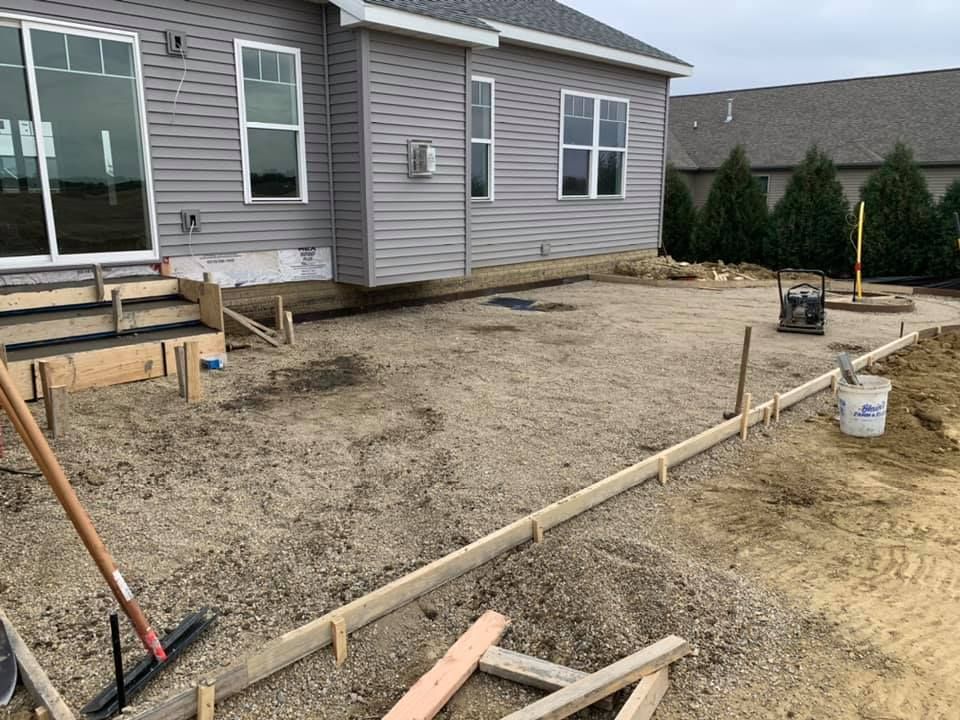 Bobcat track loader on a baseball field near a home base, cloudy day.