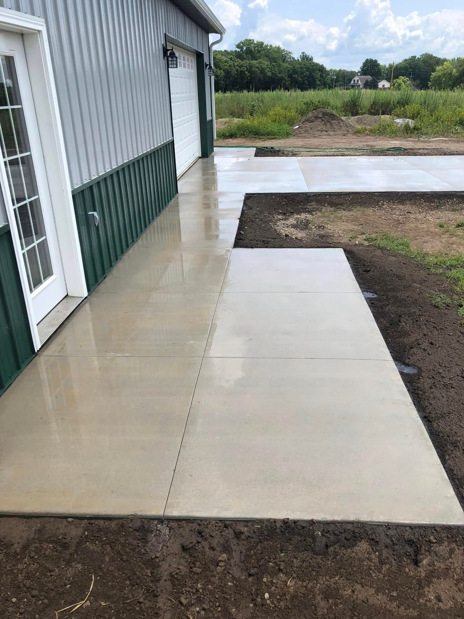 Gravel driveway with metal reinforcement grid, next to brick column, ready for concrete.