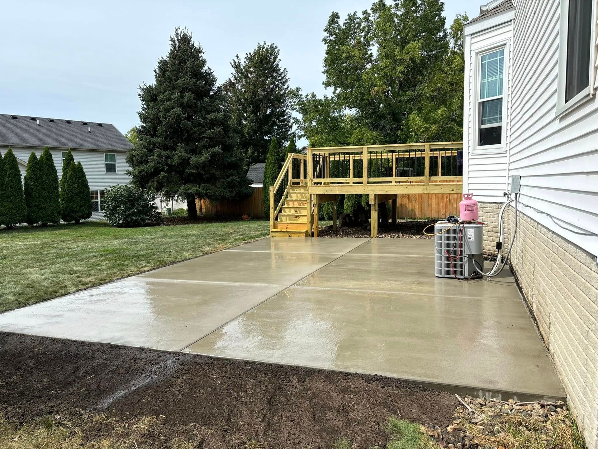 Pool construction site with a worker installing tiles, surrounded by concrete walls and earthmoving equipment.