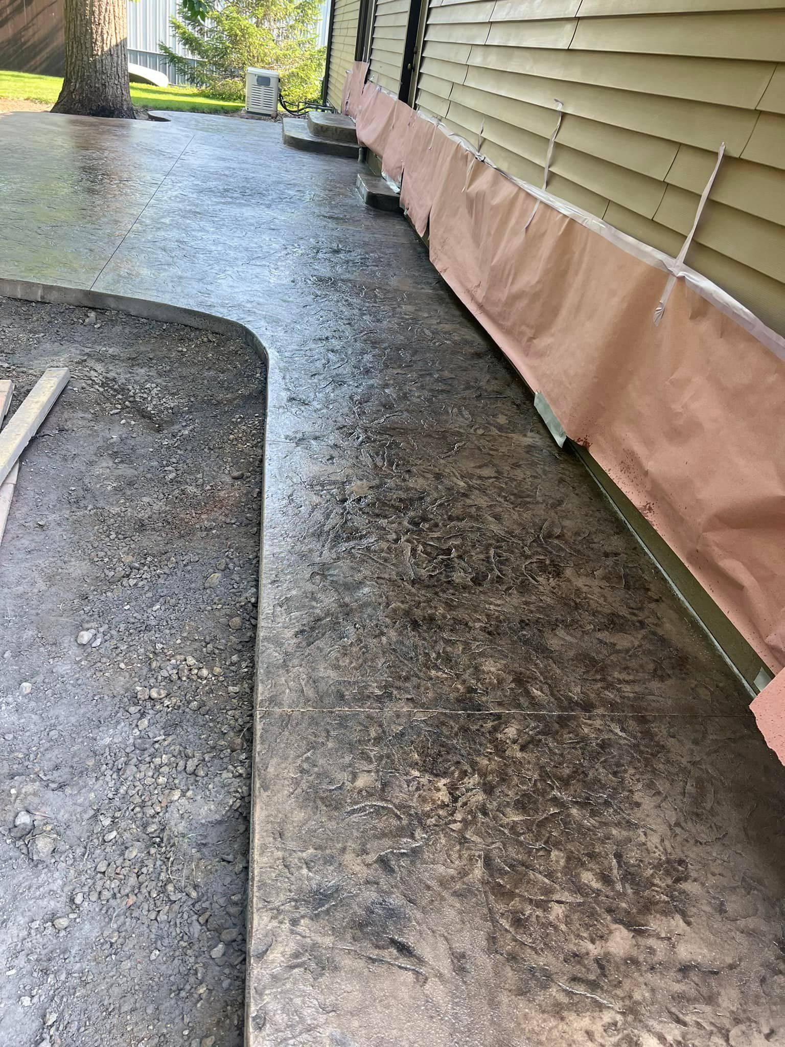 Concrete walkway next to a building, partially covered with brown protective material.