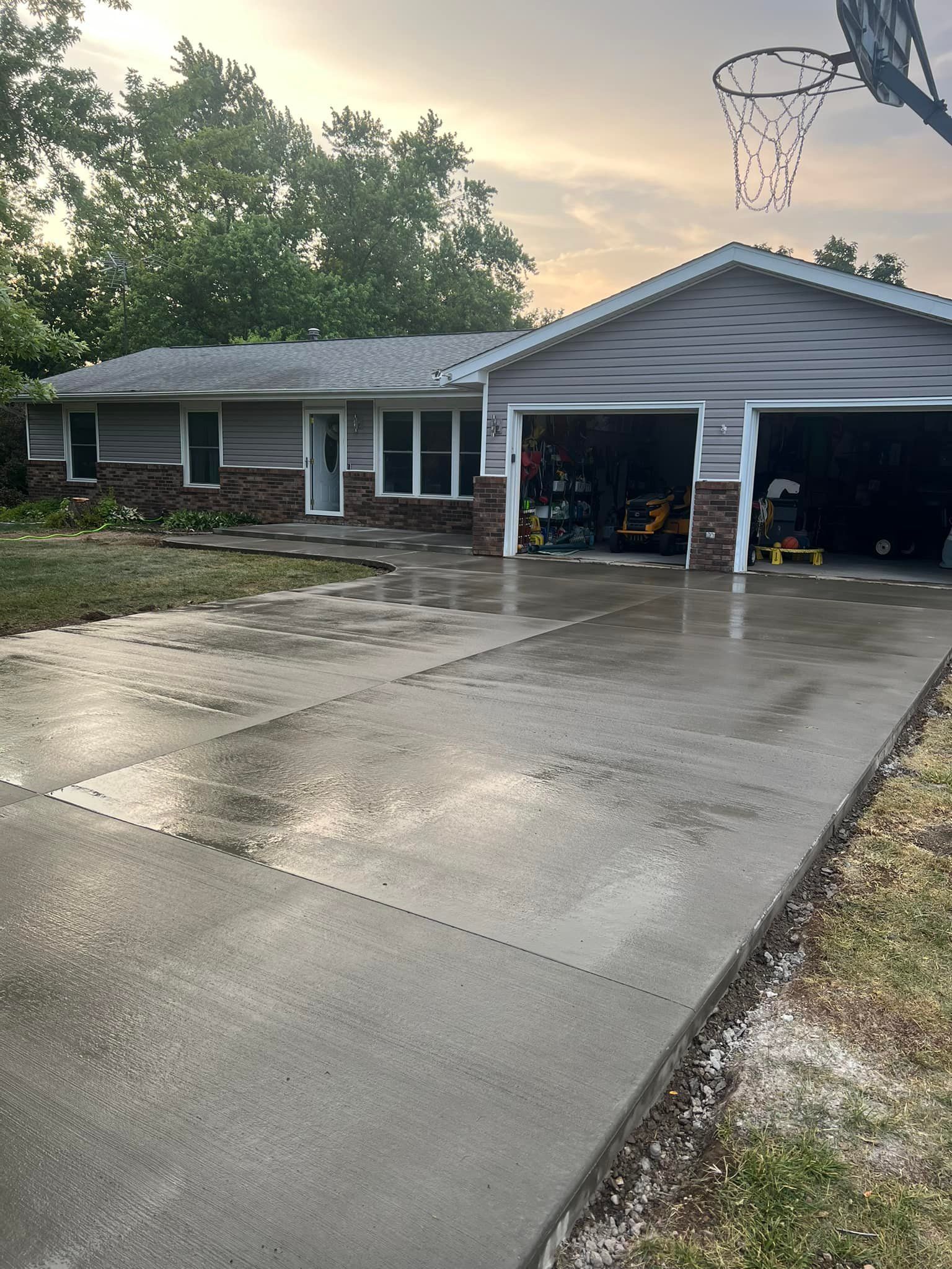 A parking lot with a section of asphalt removed, revealing gravel base, trailer in background.