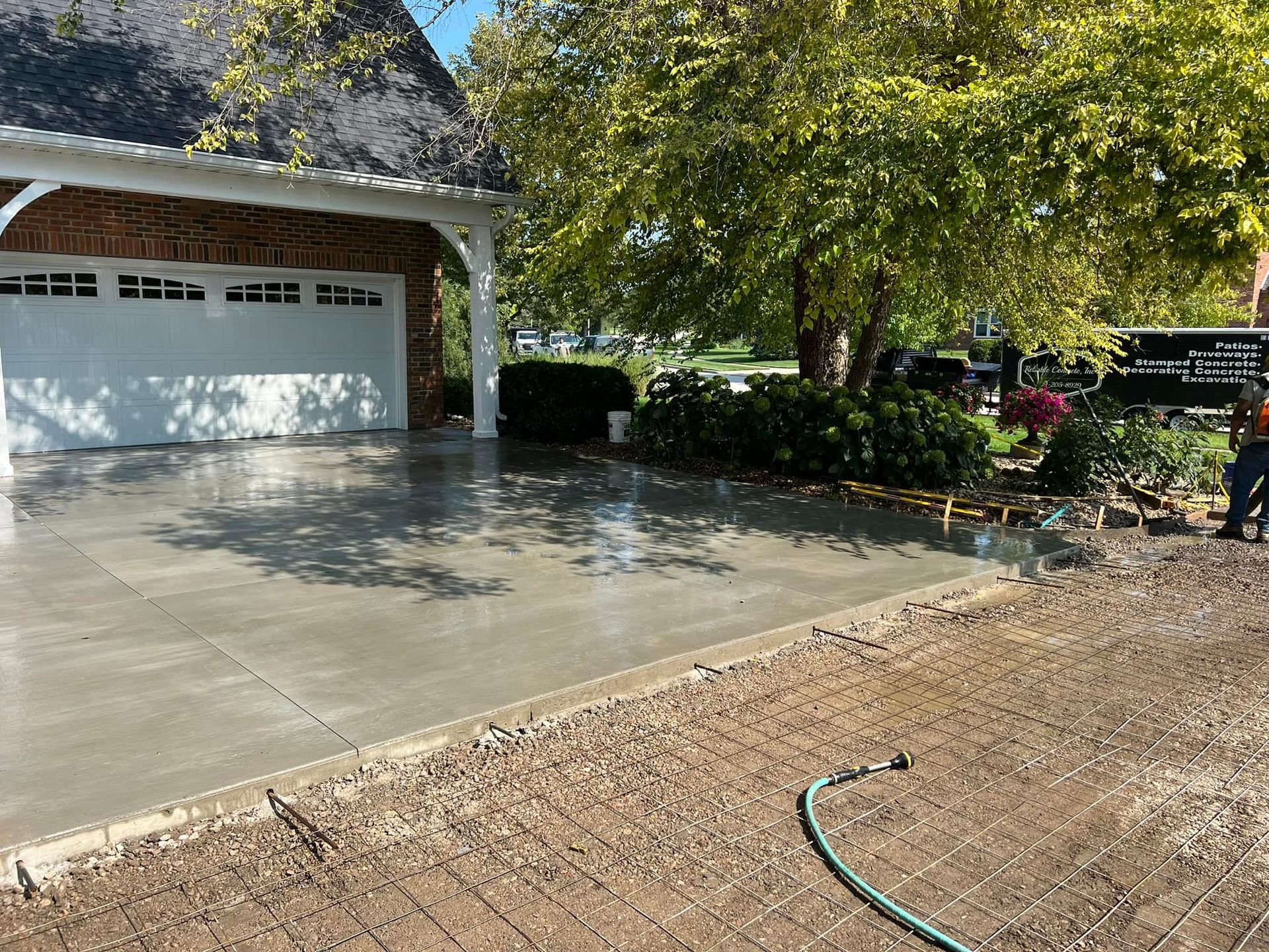 A concrete parking lot in front of a light brown building with parked cars and a clear, cloudy sky.