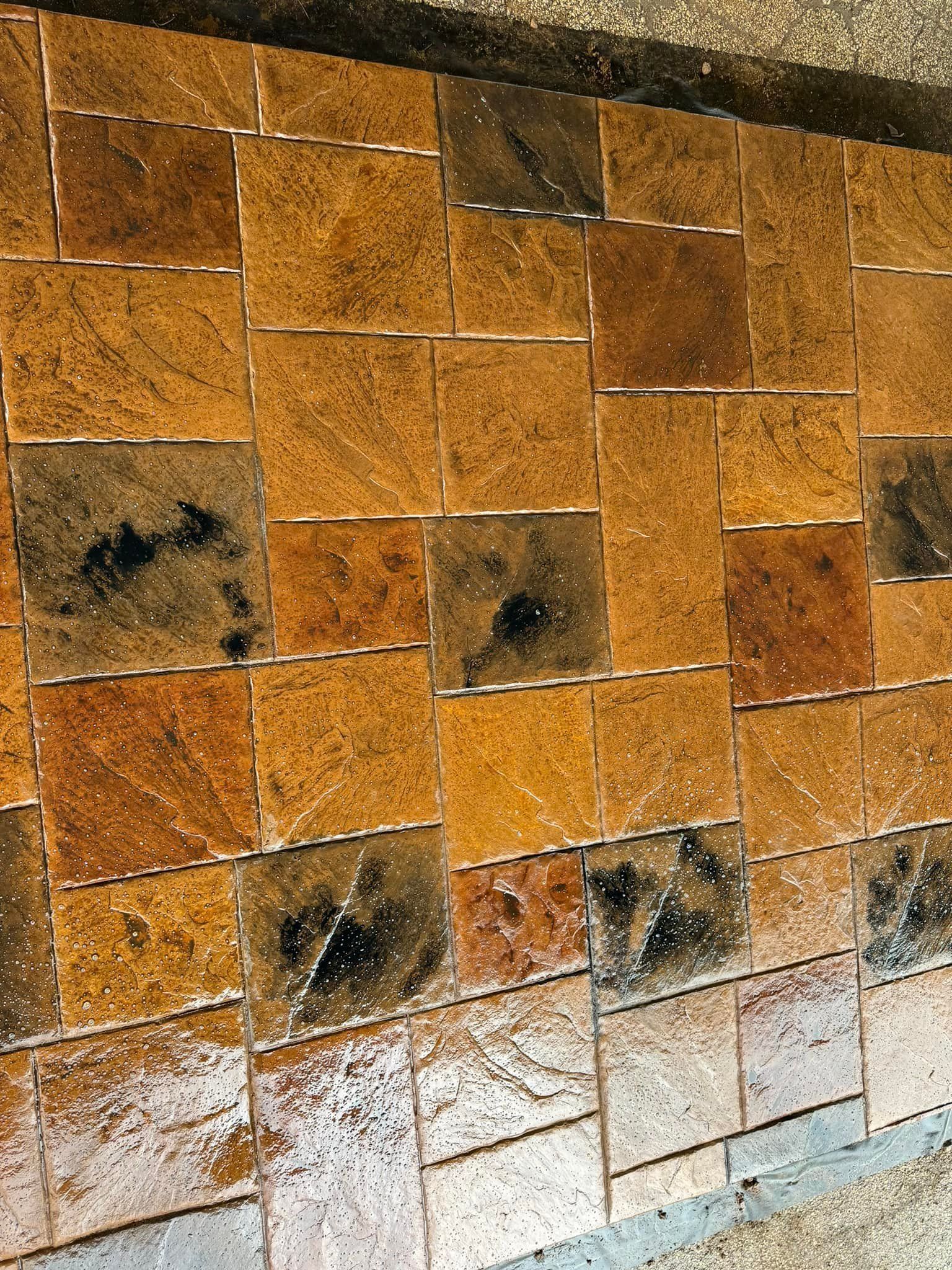 Square brown tiles laid out, with dark, wet patches.