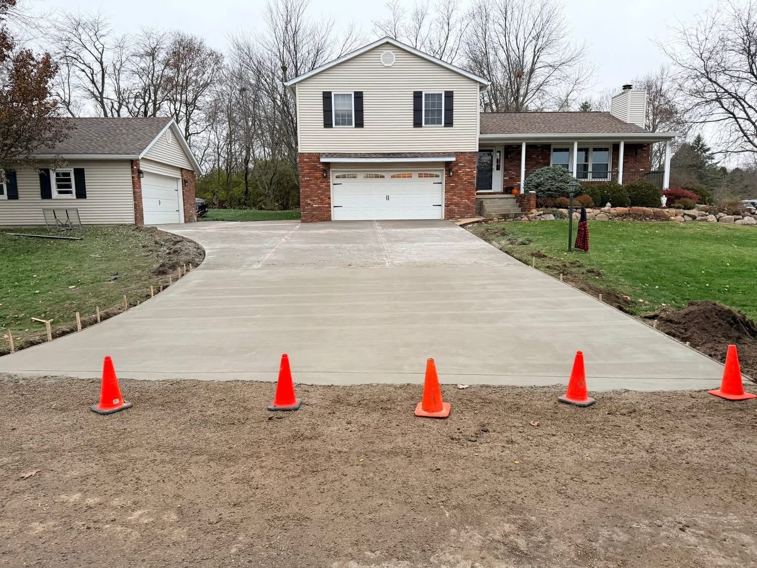 Gray speckled epoxy-coated concrete porch floor, next to a darker concrete sidewalk, leading to a white door.