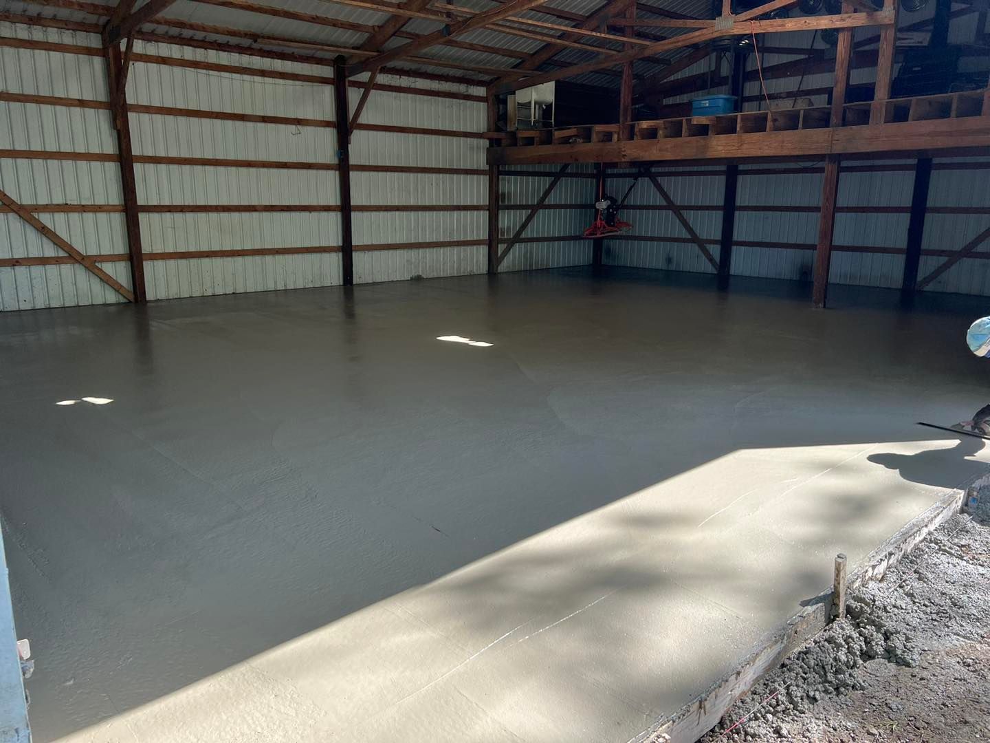 Gray concrete patio with fire pit, dining set on the side, and green grass.