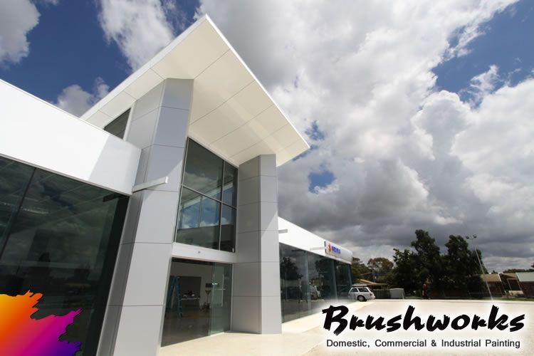 Modern building with white and silver facade, glass windows, and the name