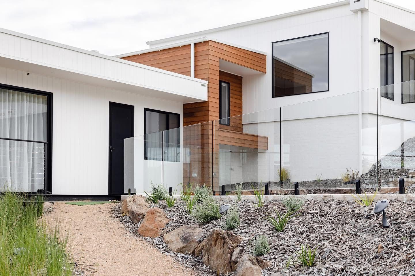 A Man is Standing on a Ladder Painting a House — Brushworks Painting In Lavington, NSW.