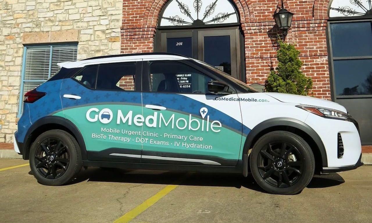 A man in a blue scrub is smiling with his arms crossed