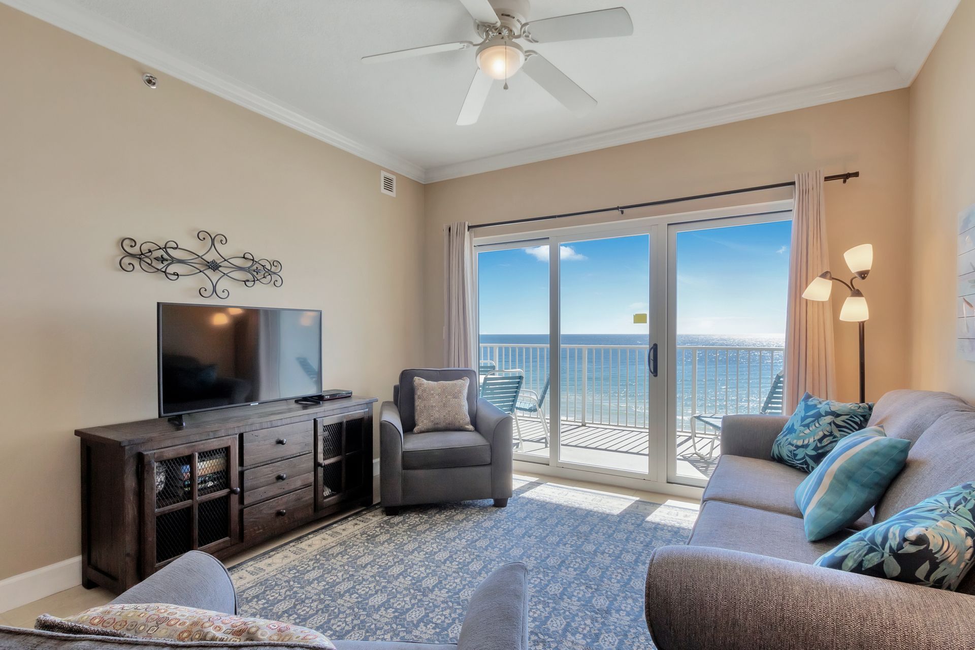 Living room with ocean view, gray furniture, TV, and a sliding door to a balcony.