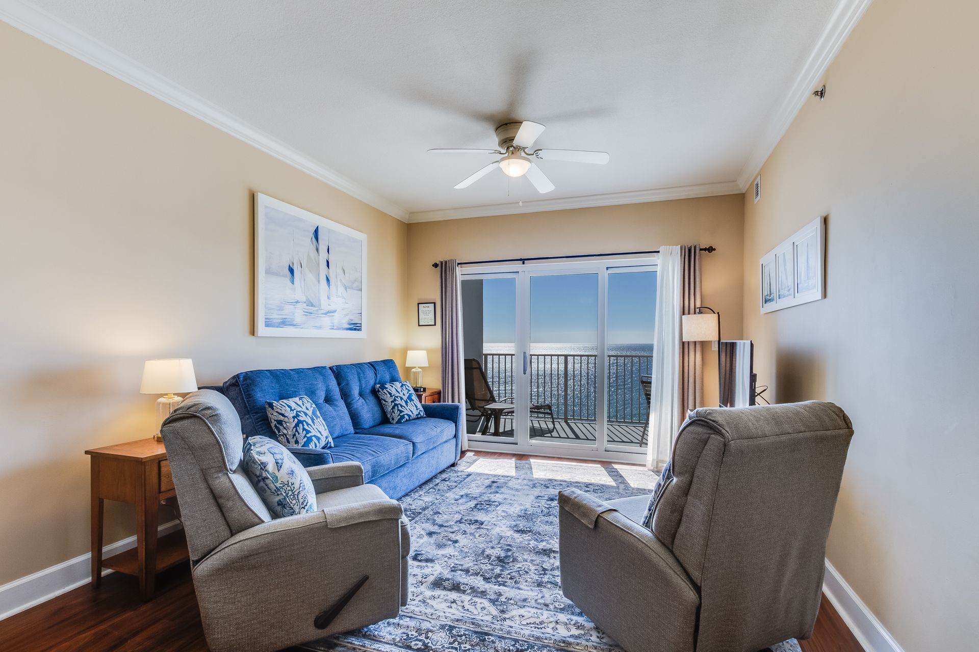 Living room with blue sofa, recliners, ocean view balcony.