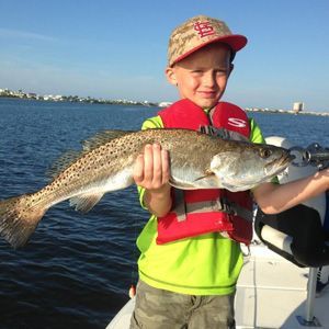 A young boy is holding a large fish on a boat.