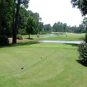 A golf course with trees and a pond in the background