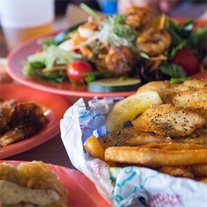 A basket of french fries sits on a table next to a plate of food.