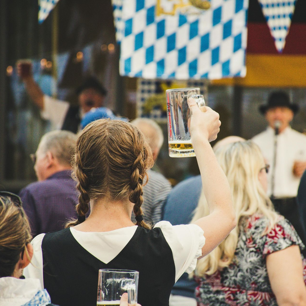 A woman is holding a glass of beer in front of a crowd of people.
