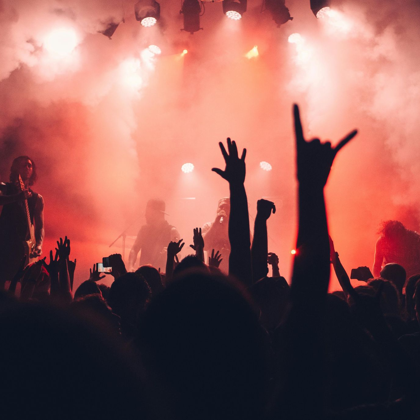 A crowd of people at a concert with their hands in the air.