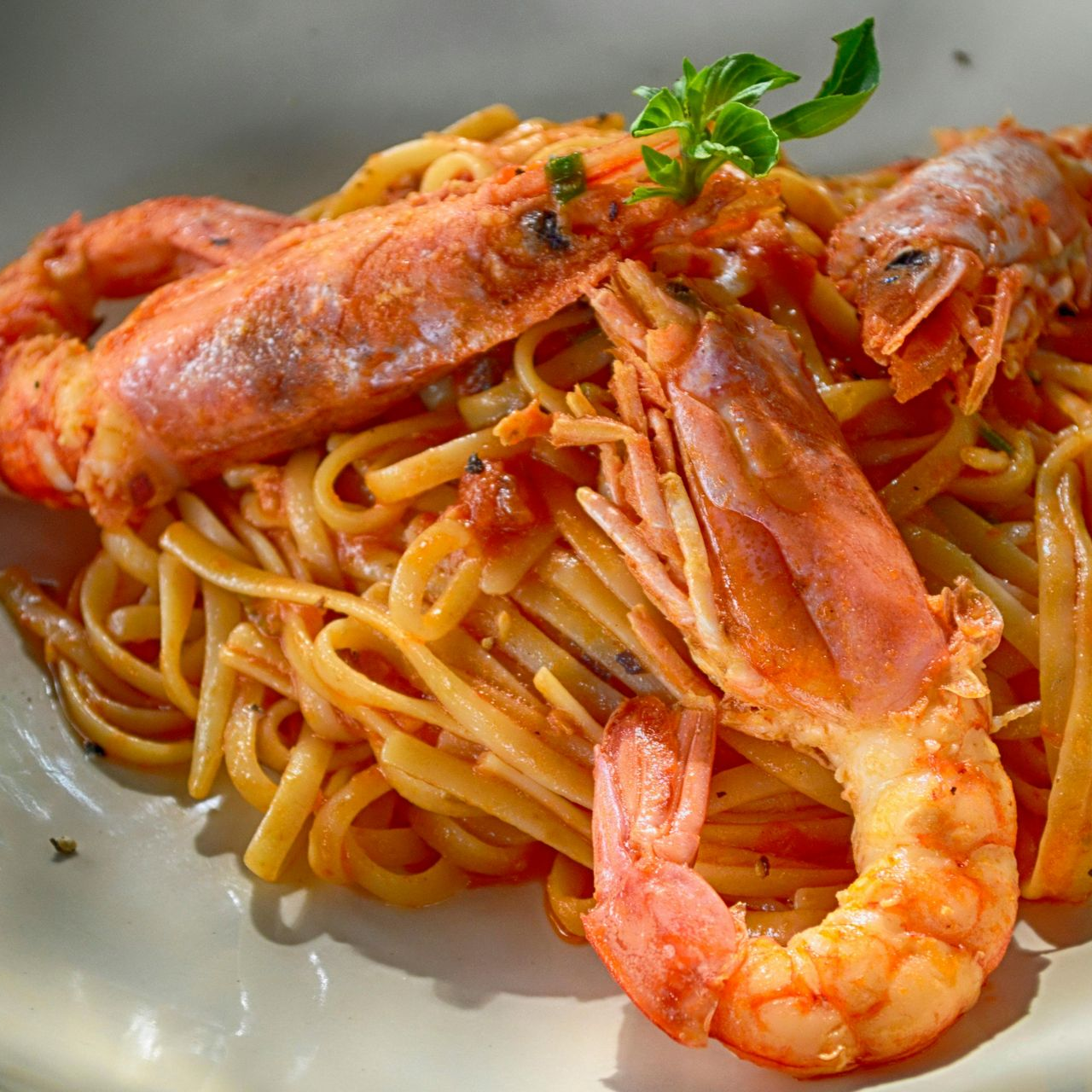 A plate of spaghetti with shrimp and sauce on a table.
