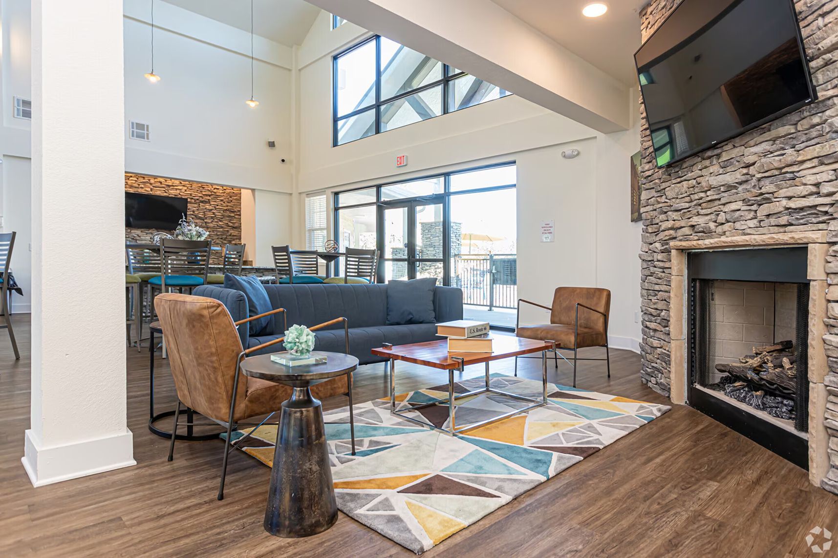 Cozy resident lounge with stone fireplace, comfortable seating, and large windows at Waypoint at Hammond.