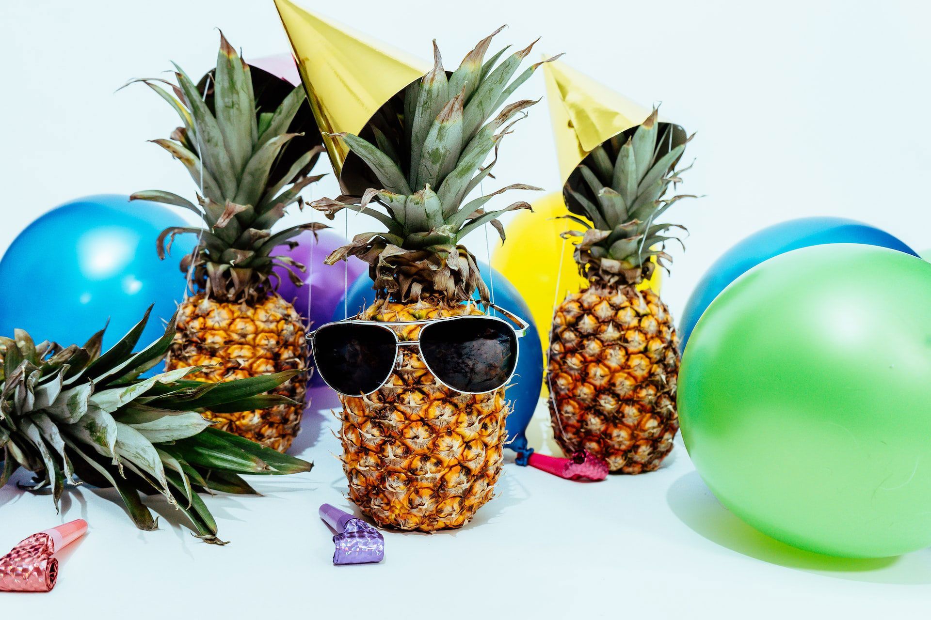 pinapple with sunglasses surrounded by balloons