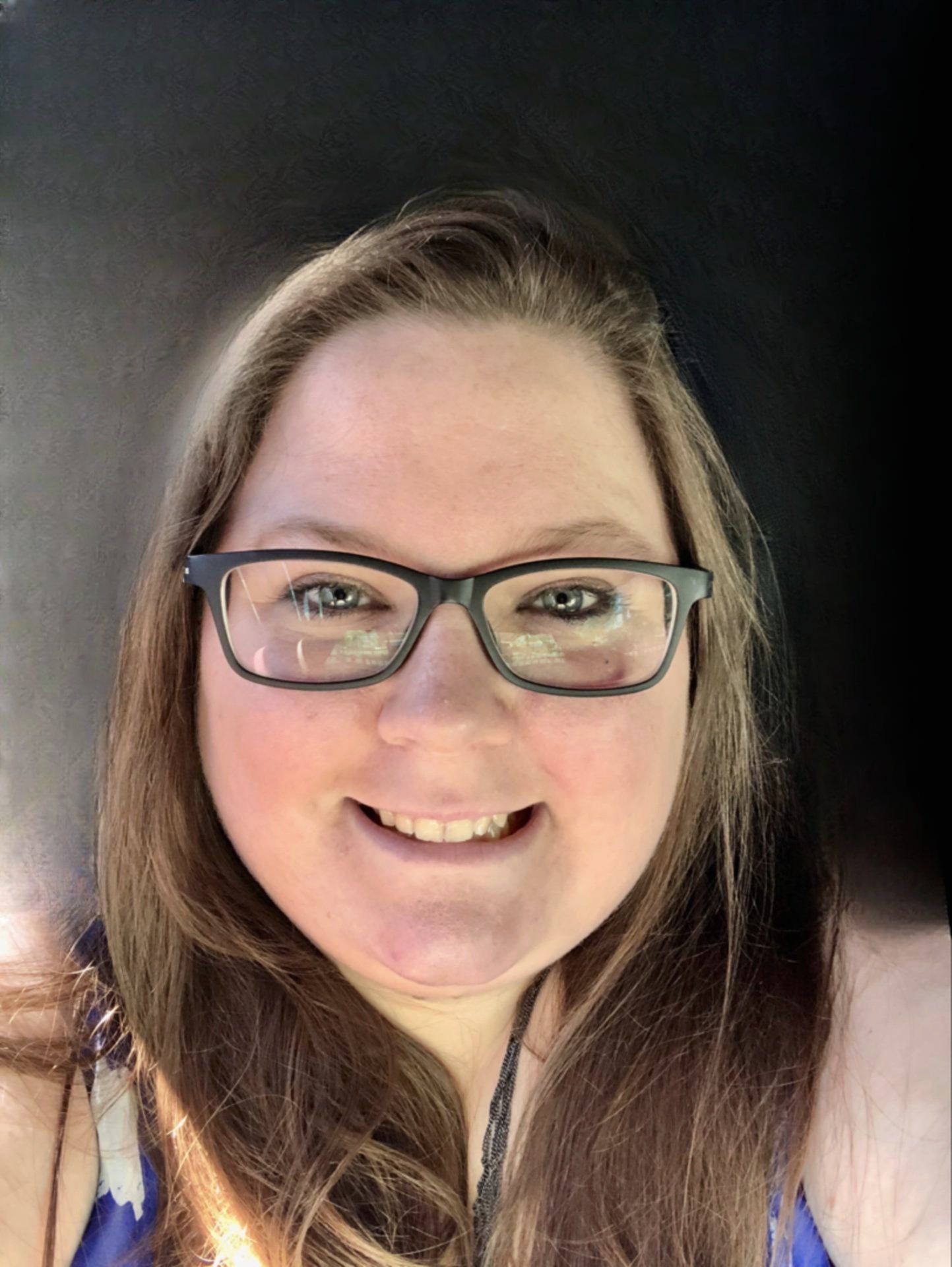 A woman wearing glasses is smiling for the camera.