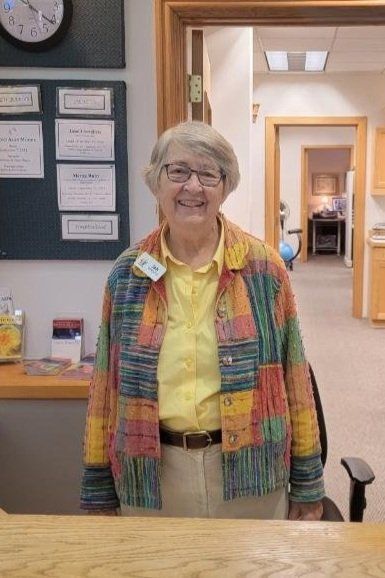 A woman in a colorful jacket is standing behind a counter