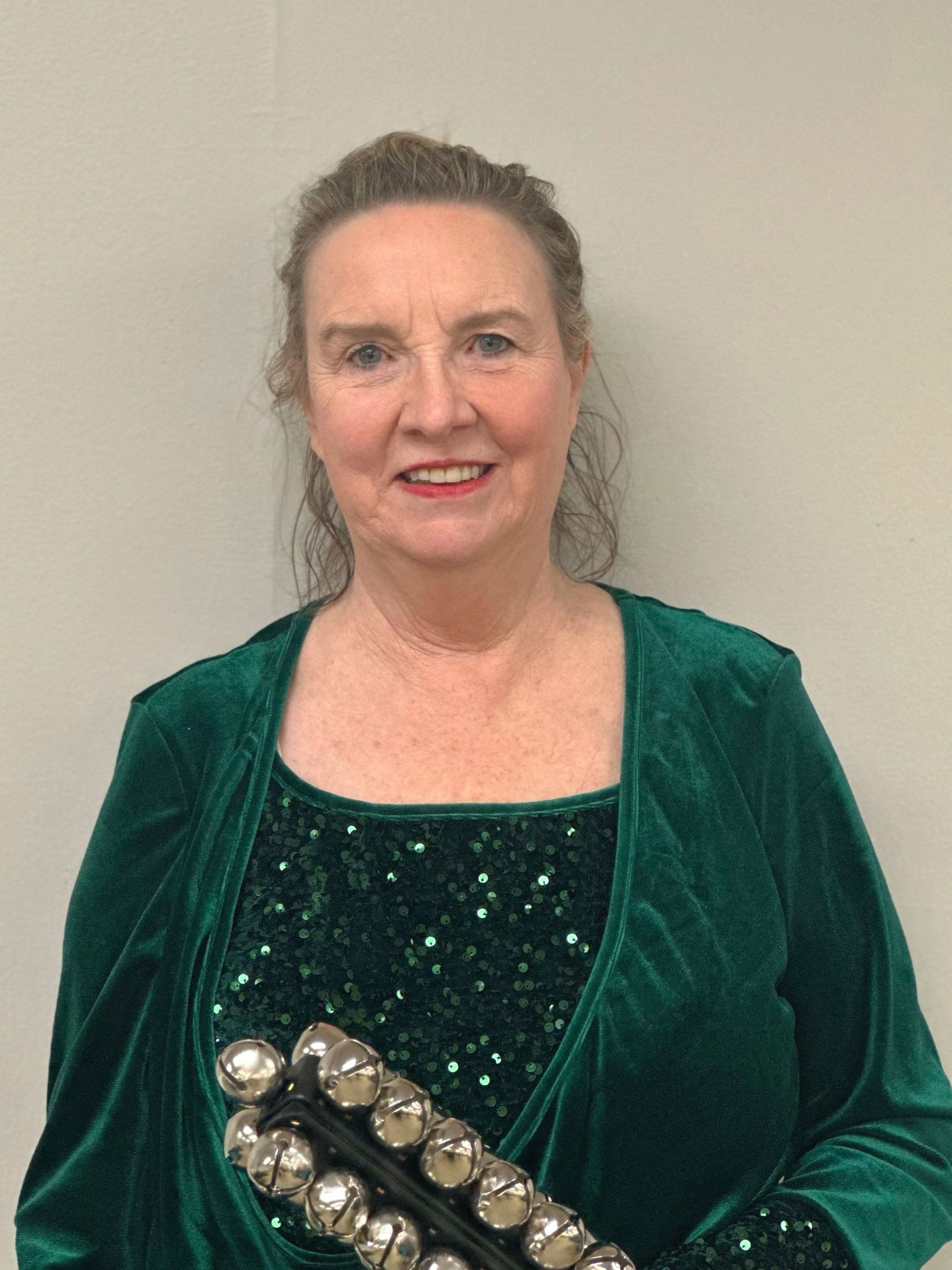 A woman in a green dress is holding a tambourine.