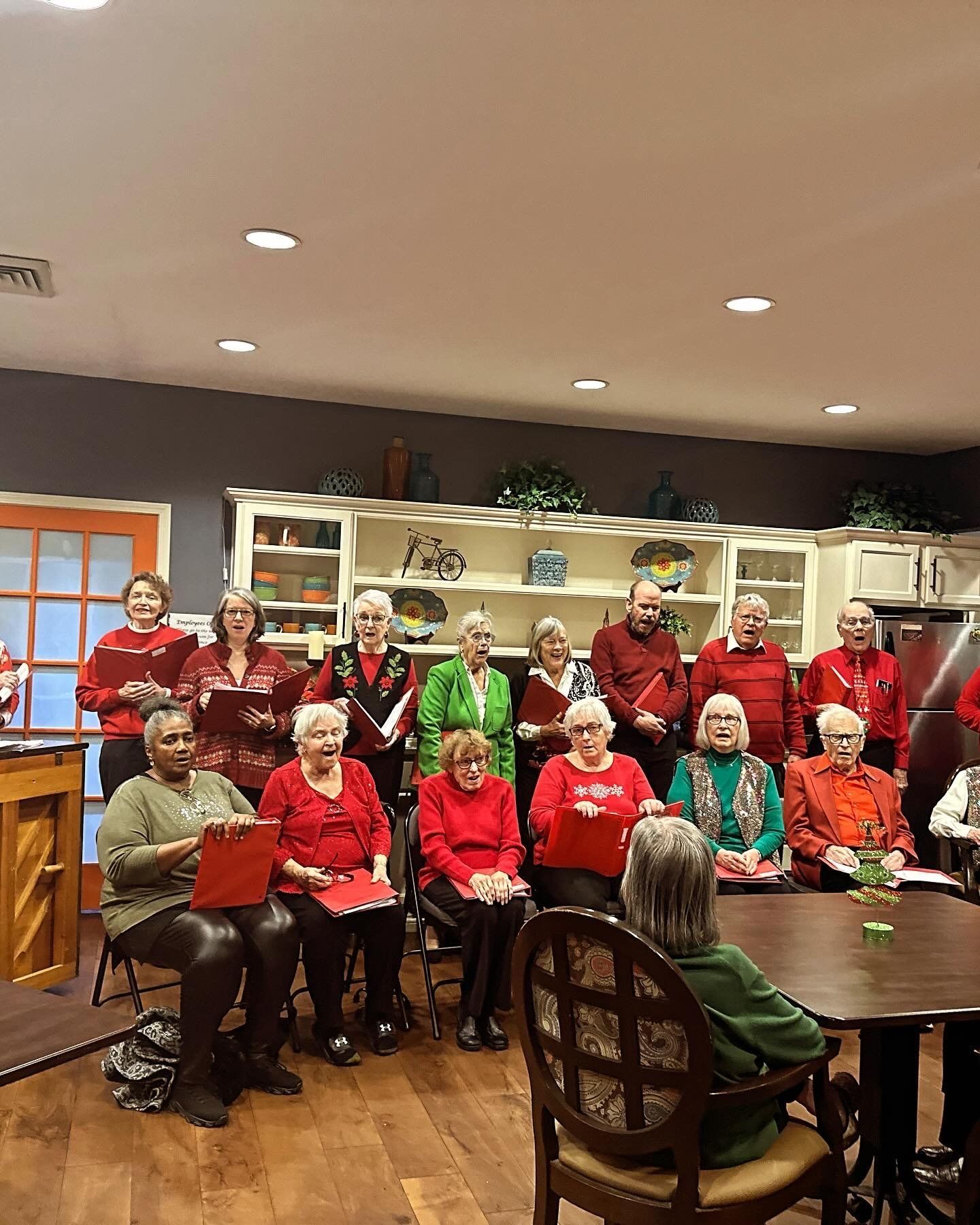 A group of people are sitting around a table singing in a choir.