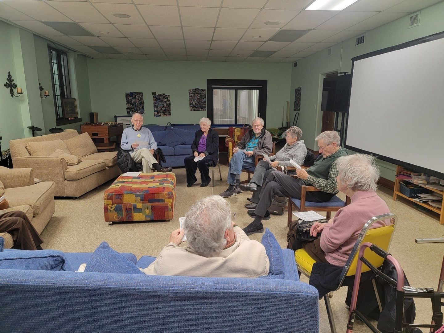 A group of elderly people are sitting in a circle in a living room.
