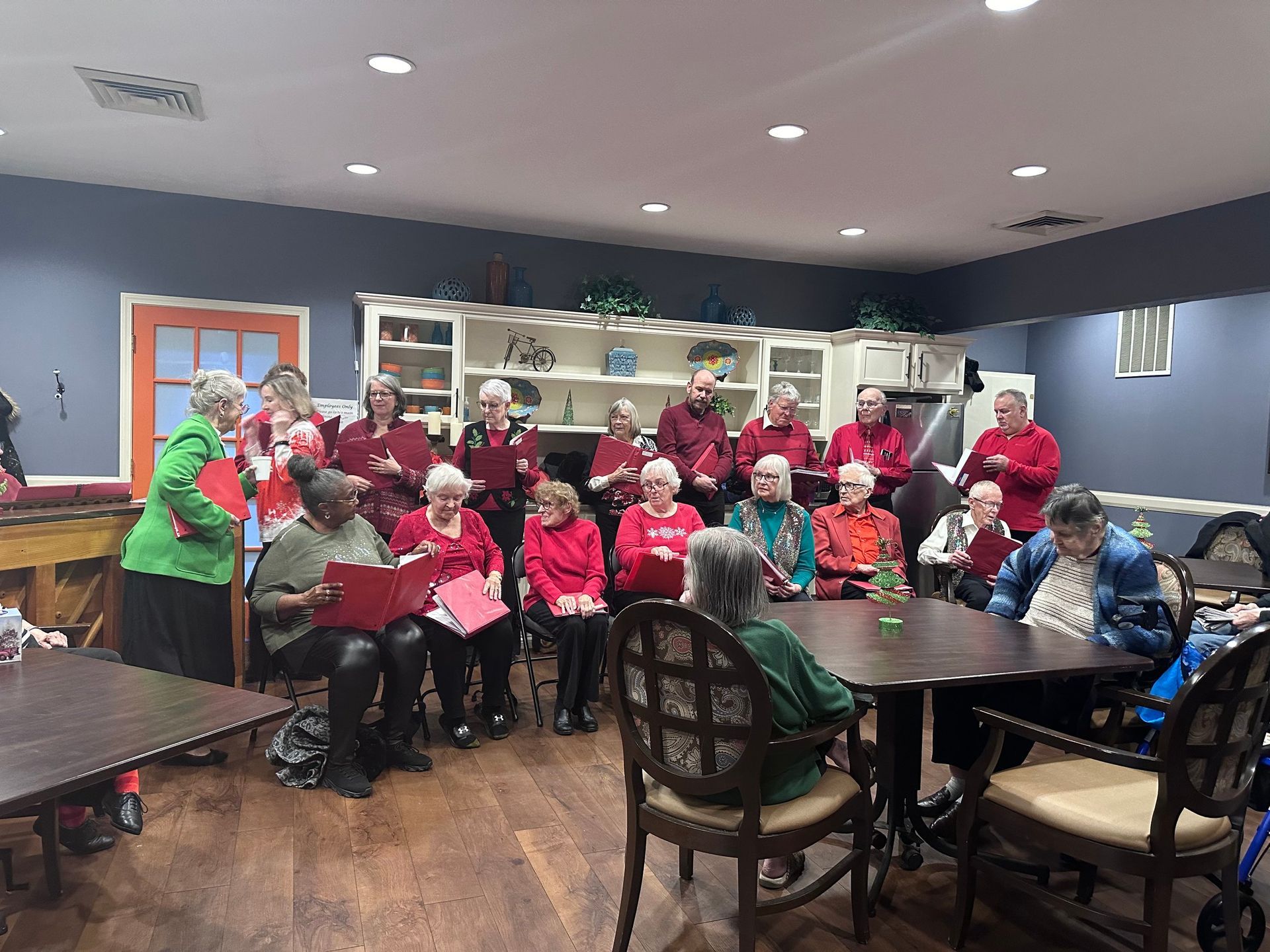A group of people are sitting at tables and singing in a room.