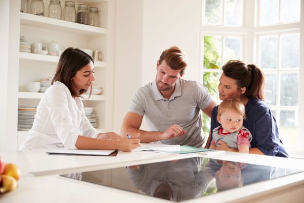 A large family is sitting at a table eating food.