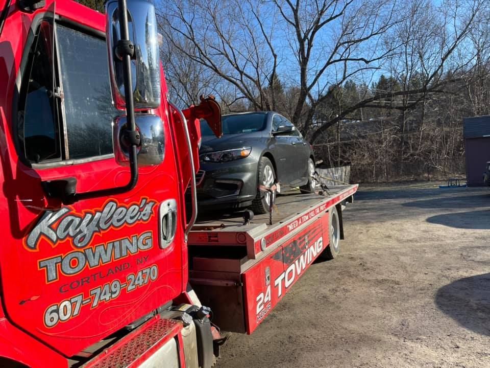 A red towing truck with a car on the back of it.