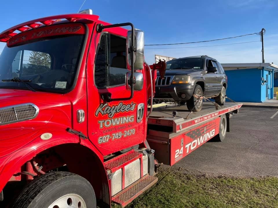 A red towing truck with a jeep on the back of it.