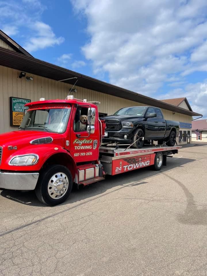 A red tow truck is towing a black truck.