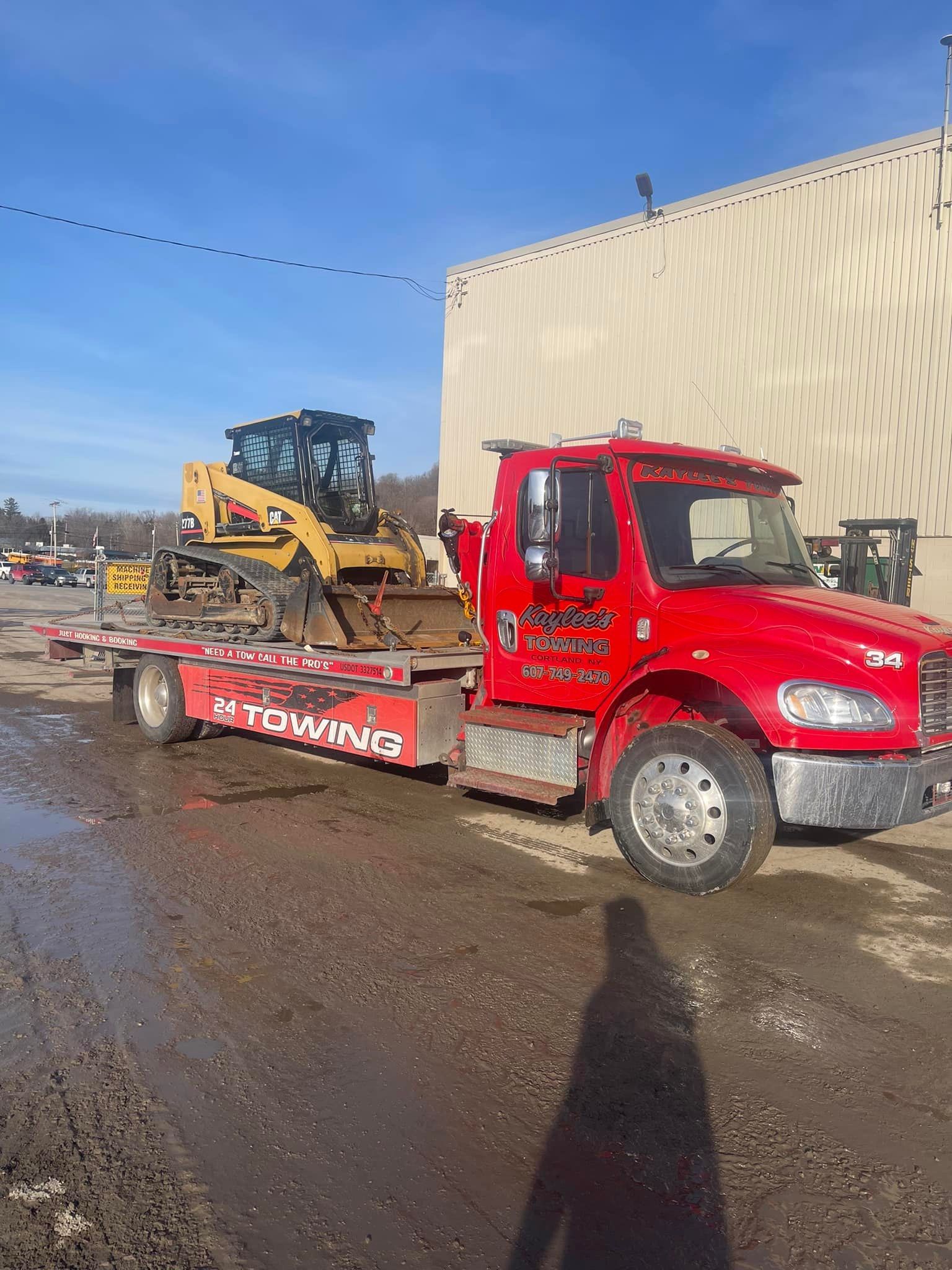 A red tow truck is carrying a yellow bulldozer on a trailer.