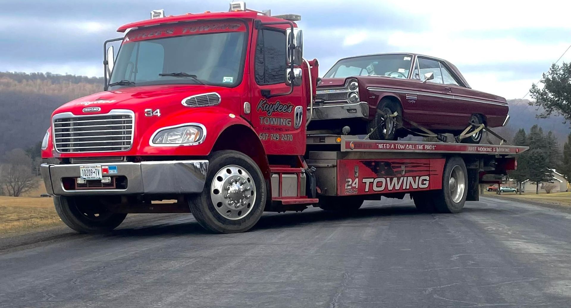 A red tow truck is carrying a car on the back of it.