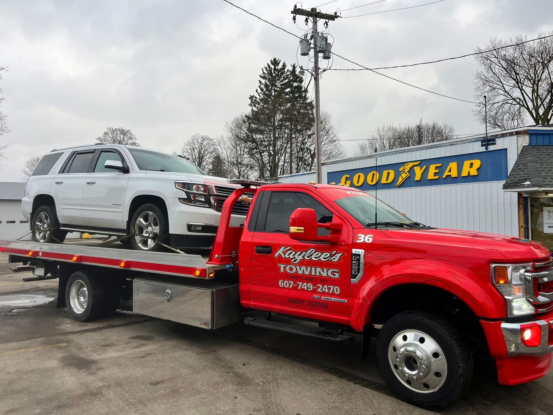 A red tow truck is towing a white suv.
