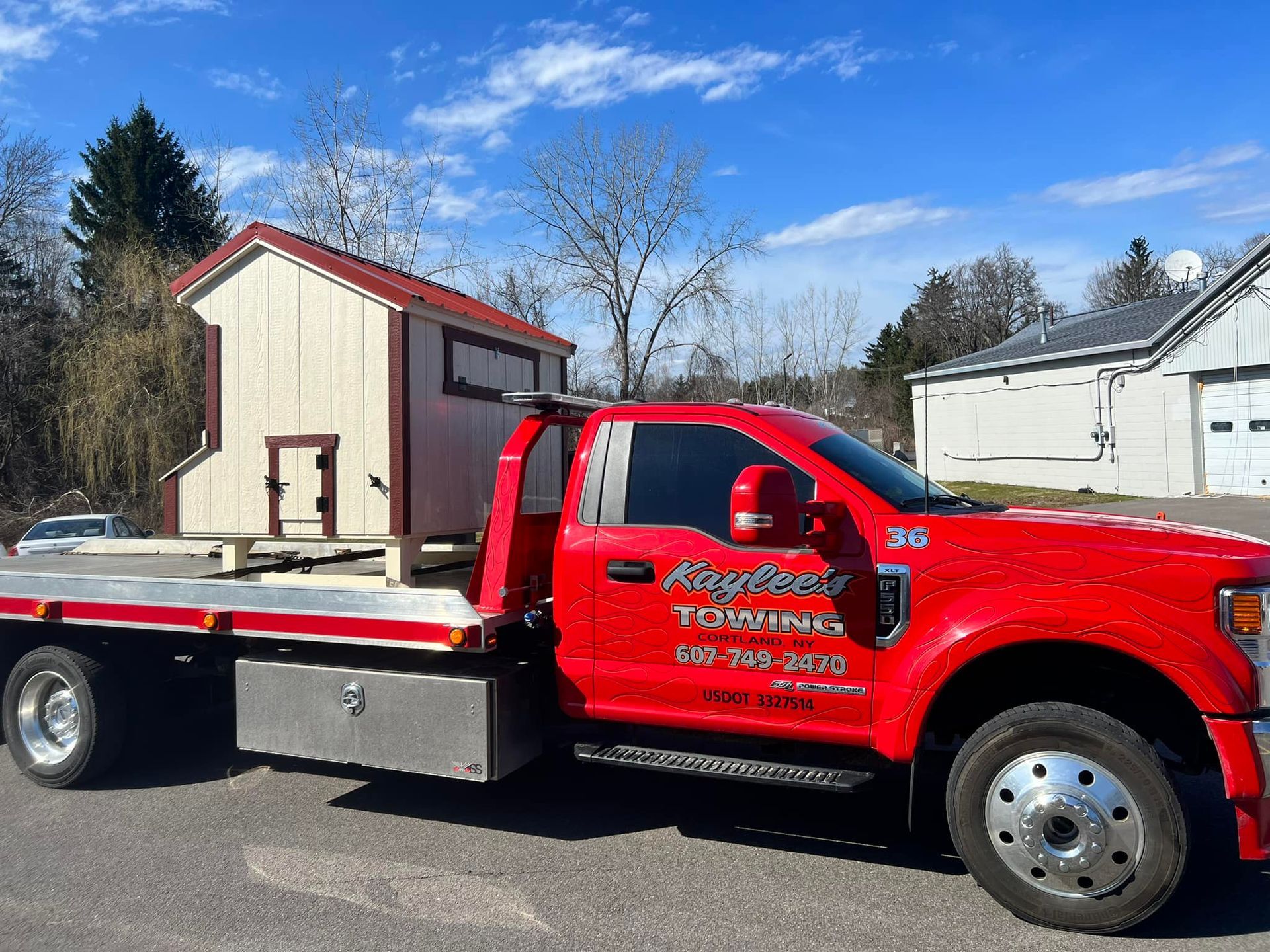 A red tow truck with a shed on the back is parked in front of a house.